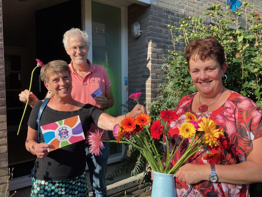 Vrijwilligers van Lief en Leedstraten delen bloemen uit.