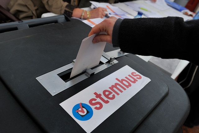 Stembus waar een hand een stembiljet ingooit.