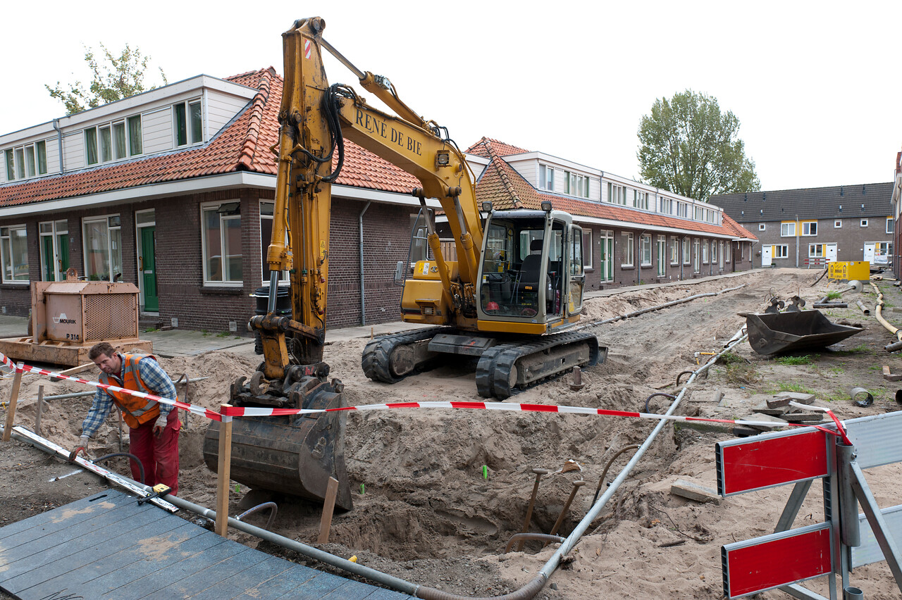 Een kraan in de wijk Korte Akkeren graaft een gat in een straat die open ligt.