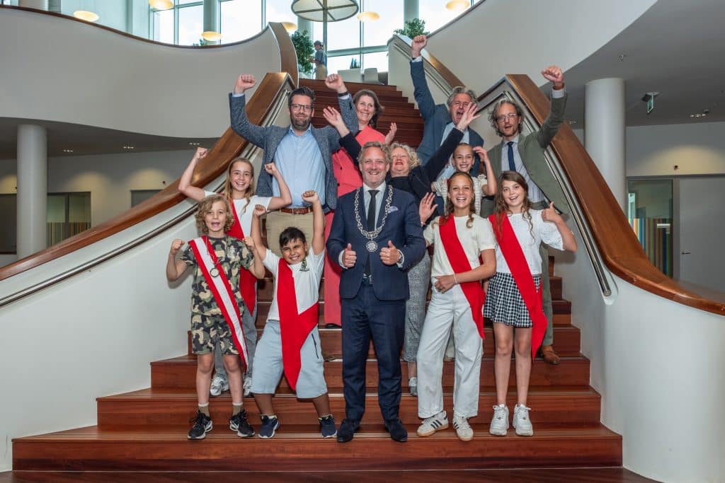 Het college en het kindercollege met z'n allen op de foto op de trap van het Huis van de Stad. Met Fenne Slingerland, Isabel Hagoort, Lida Kharytonova, Robin van der Sar, Adam Bouysaghouan.