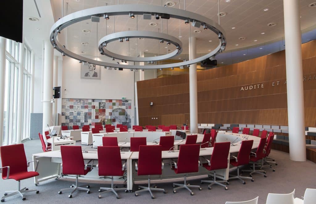 Foto van de Raadzaal in het Huis van de stad. In de zaal staan verschillende rode stoelen.